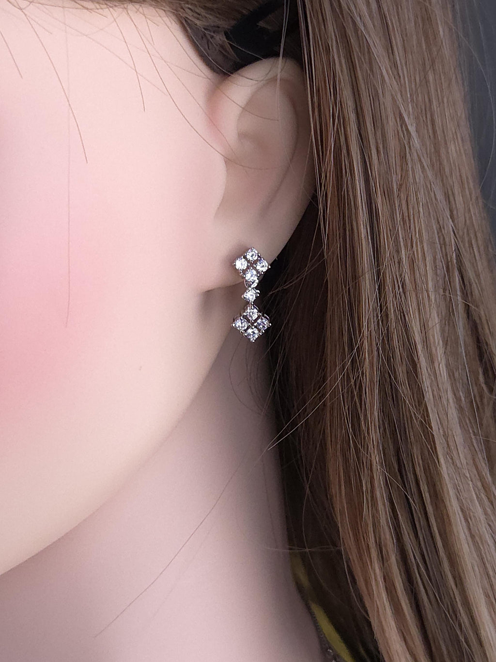 Close-up of a person wearing a diamond earring with a soft background