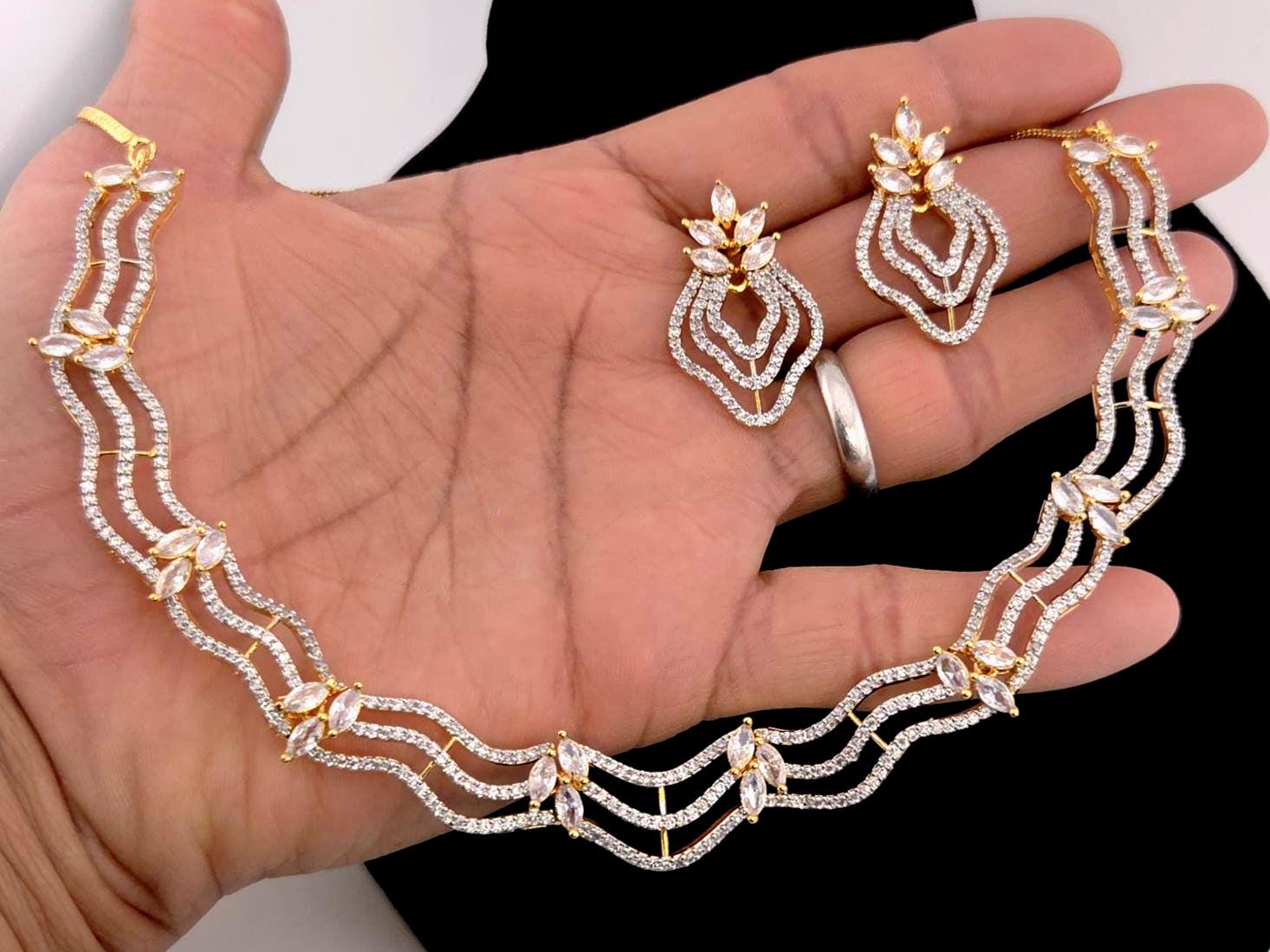 Gold and diamond jewelry set on a hand against a white background