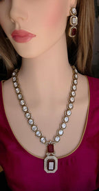 Mannequin wearing a decorative necklace and earrings with red and white stones.