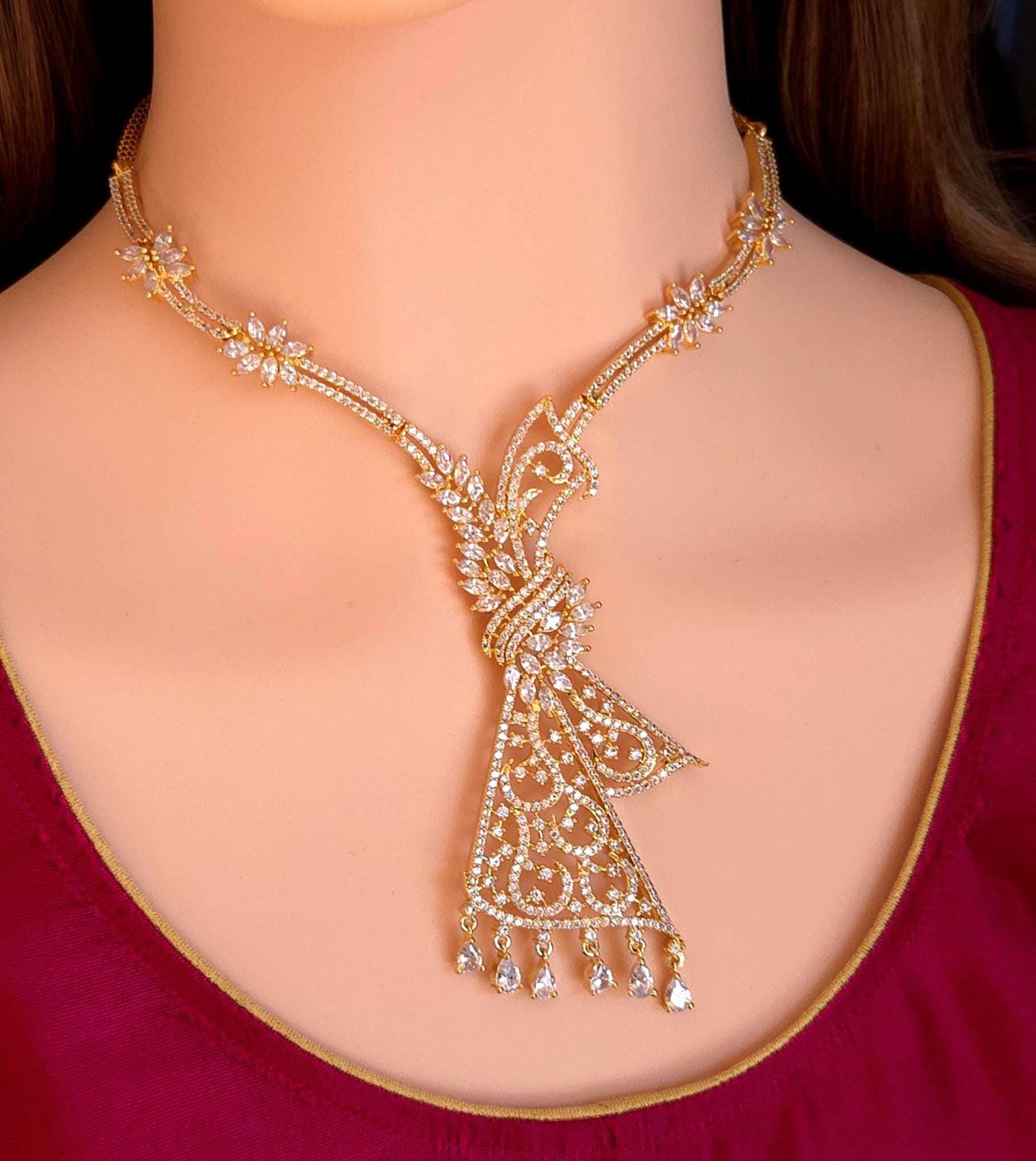 Long peacock chandelier earrings for Pakistani wedding baraat, Indian bridal mehndi jewelry with teardrop CZ stones. Hand holding matching long filigree earrings, gold plated cubic zirconia Indian wedding earrings for reception look