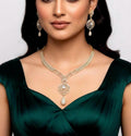 Woman wearing a gold necklace and earrings on a plain background