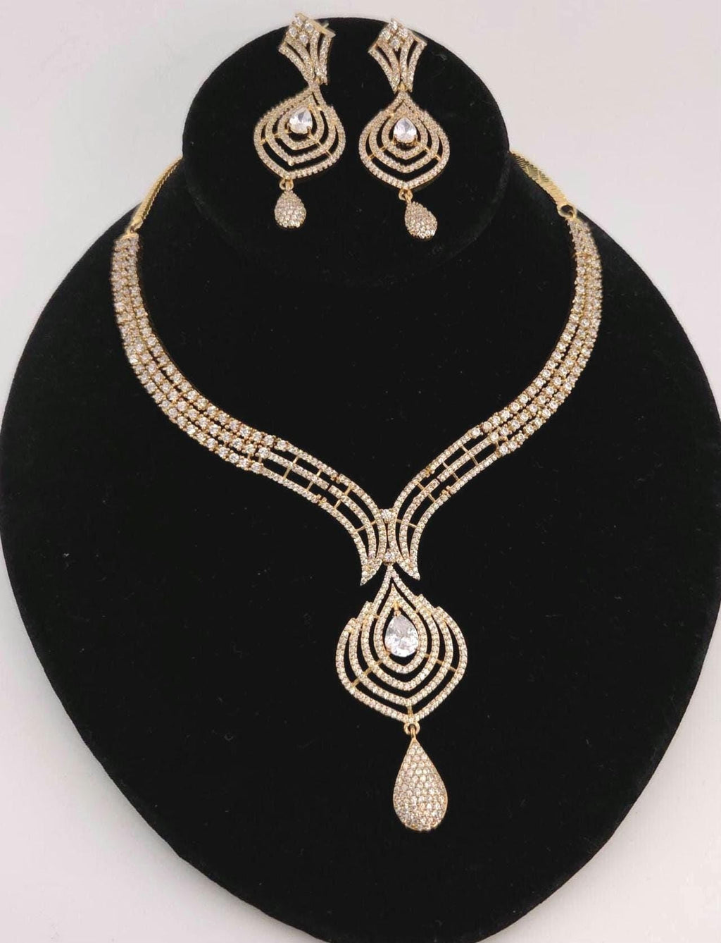 Gold necklace and earrings set on a black stand