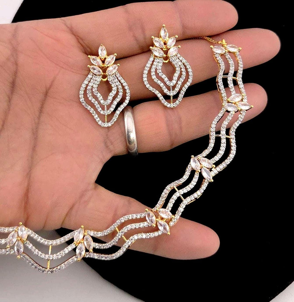 Jewelry set including necklace, earrings, and ring on a hand against a black background