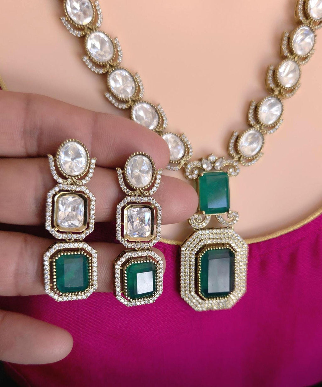 Jewelry set with necklace and earrings featuring green gemstones and gold accents.