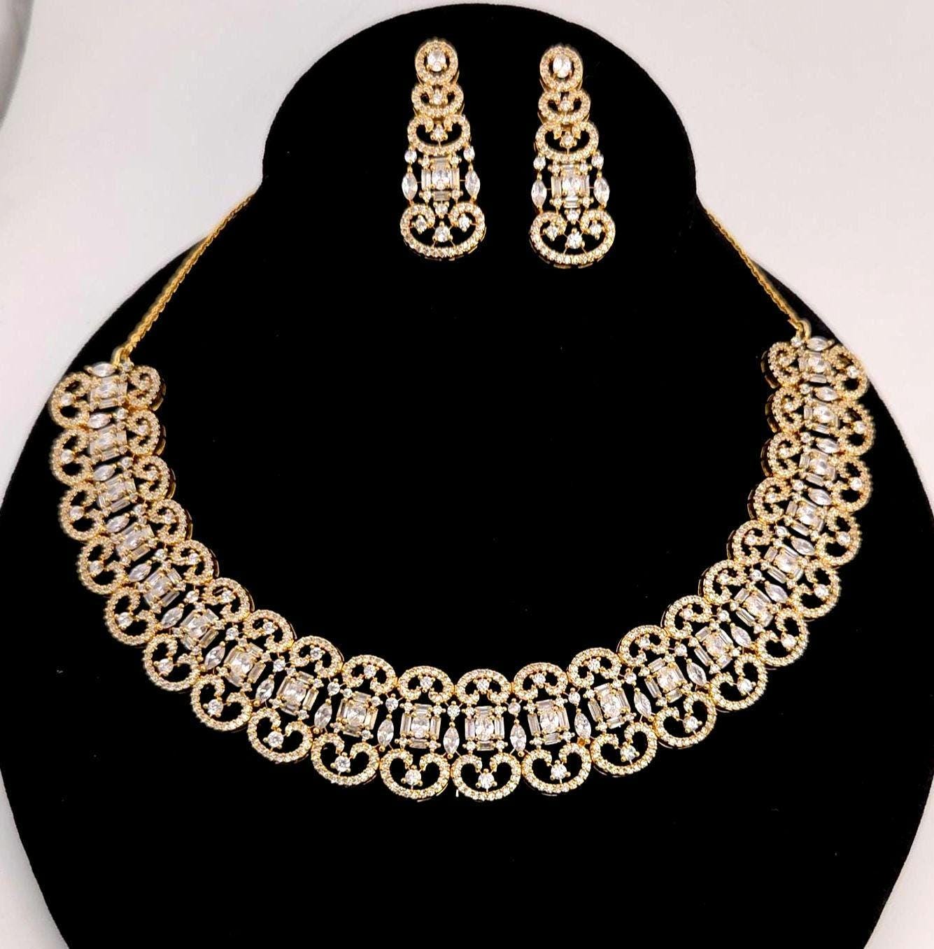 Gold necklace and earrings set on a black stand