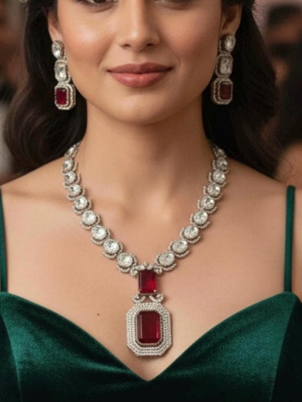 Woman wearing a luxurious diamond and red gemstone necklace with matching earrings.