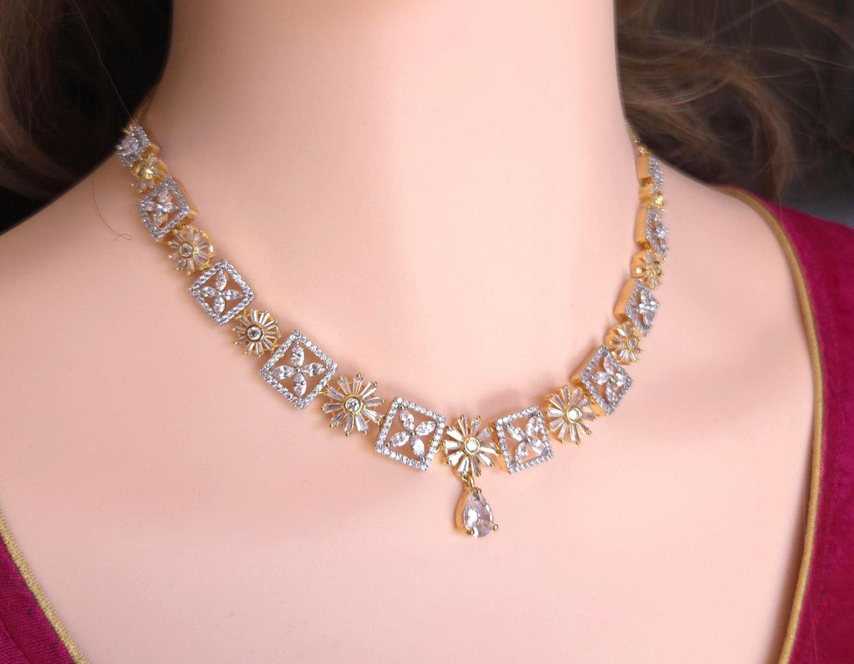A gold and silver-toned diamond necklace with floral and geometric motifs, displayed on a mannequin bust wearing a maroon top.