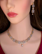 Gold and diamond necklace and matching drop earring displayed on a mannequin bust with dark brown hair and pink lips.