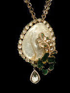 An ornate gold pendant necklace featuring a large natural pearl, green gemstone floral accents, and a dangling teardrop-shaped clear gemstone, set against a solid black background.