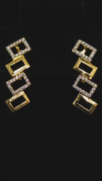 video of A gold and silver geometric jewelry set featuring a necklace and matching drop earrings, displayed on a black background.