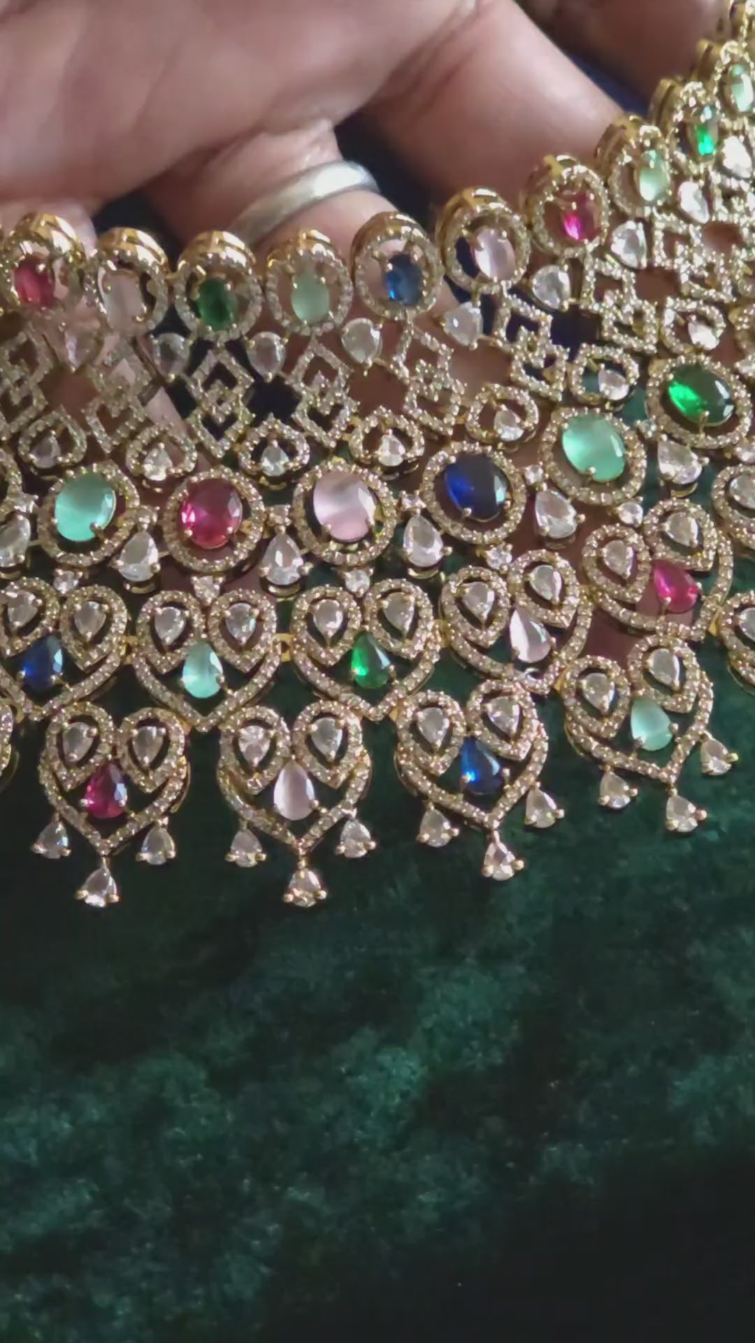 Navratan CZ Filigree Bib Choker, Chandelier Earring & Maang Tikka Bridal Set Zarkash – wide multicolor CZ filigree bib choker with emerald, ruby, sapphire, pink & white CZ stones, matching long chandelier earrings, and open-work heart maang tikka in gold finish