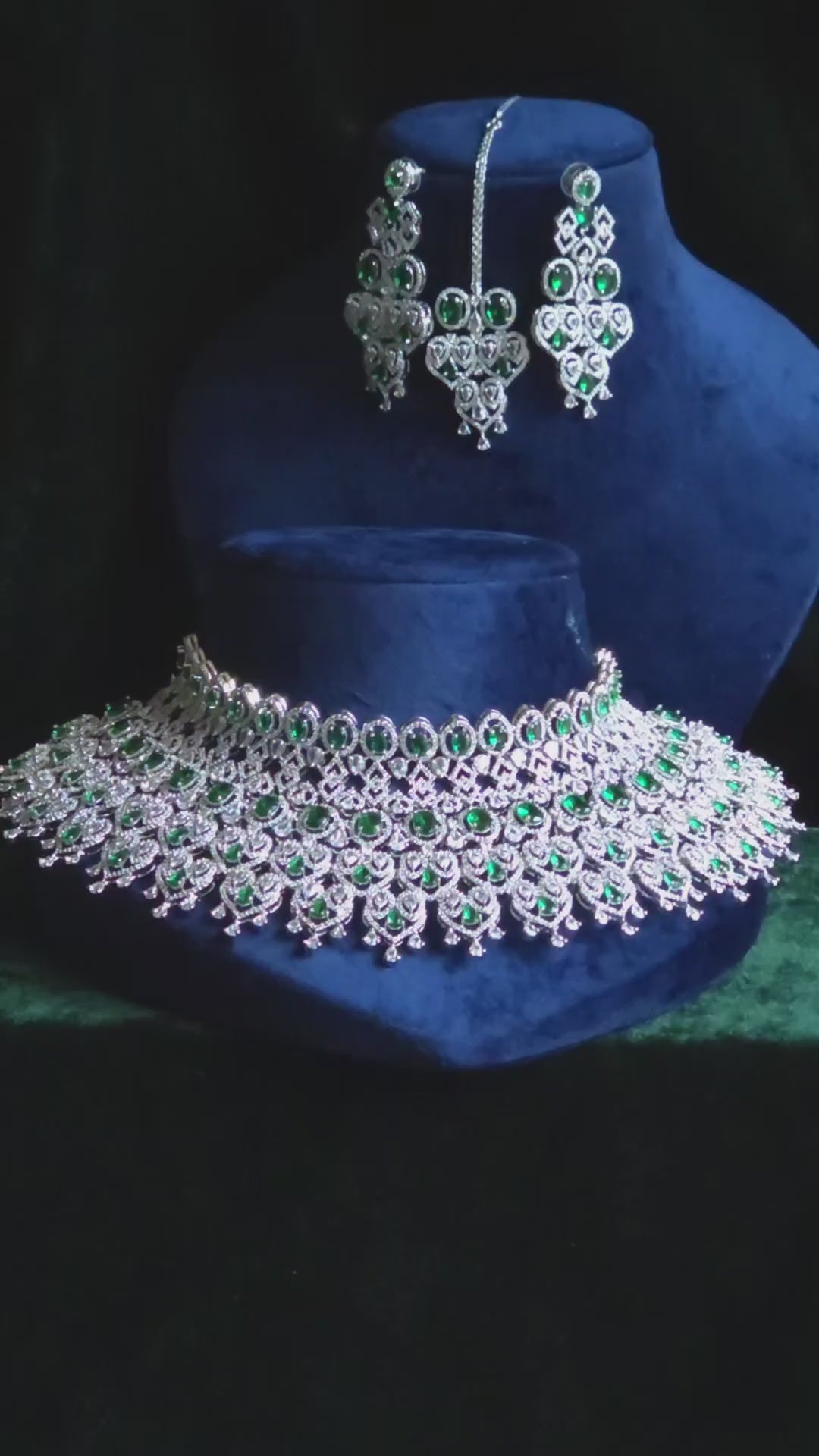 Emerald CZ Bib Choker, Chandelier Earring & Maang Tikka Bridal Set Noorjahan – wide multi-row oval emerald CZ bib choker with heart-arch teardrop fringe, long geometric chandelier earrings, and open-work heart maang tikka in silver finish