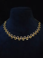 A gold and silver geometric jewelry set featuring a necklace and matching drop earrings, displayed on a black background.