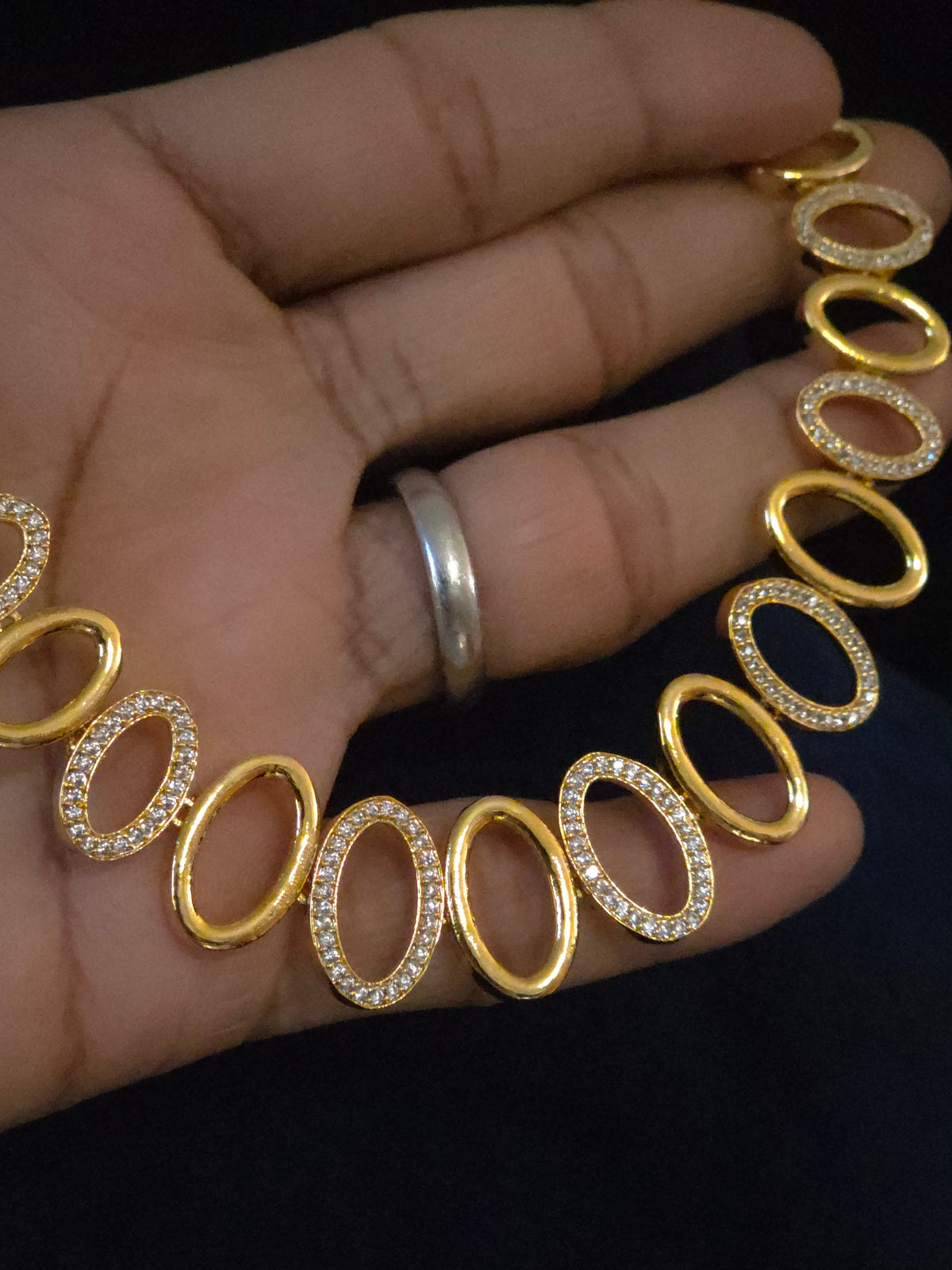 A gold oval-link necklace with alternating links set with small clear stones