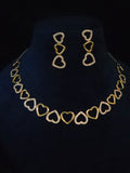 Gold heart link necklace and matching drop earrings displayed on a black velvet jewelry bust. The necklace and earrings feature alternating solid gold and open heart designs, with the open hearts embellished with small clear stones.