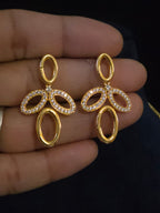 A pair of gold-tone drop earrings with oval and looped cutout details, set with small clear stones