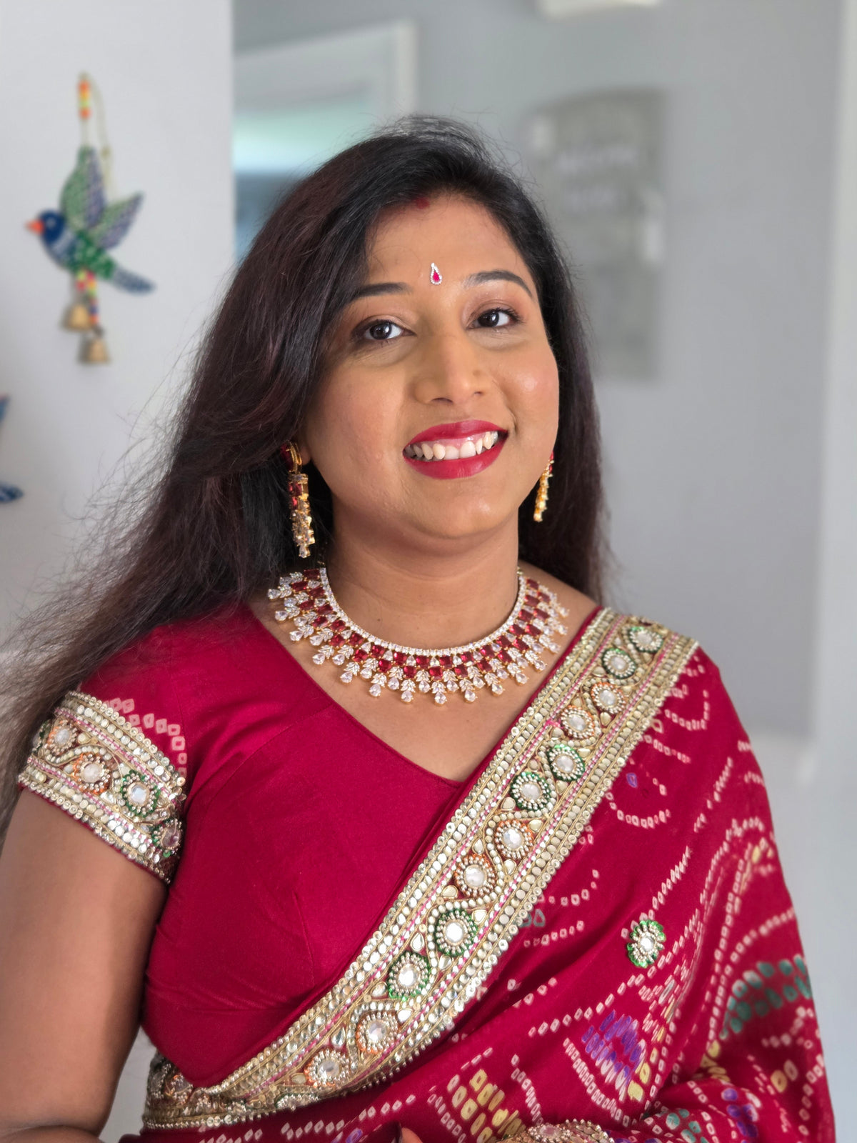 Smiling model wearing the gold-plated ruby CZ bridal choker and chandelier earrings with a red saree