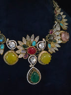 Close-up of multicolor gemstone leaf necklace showing pave leaf motifs and emerald pear drop pendant