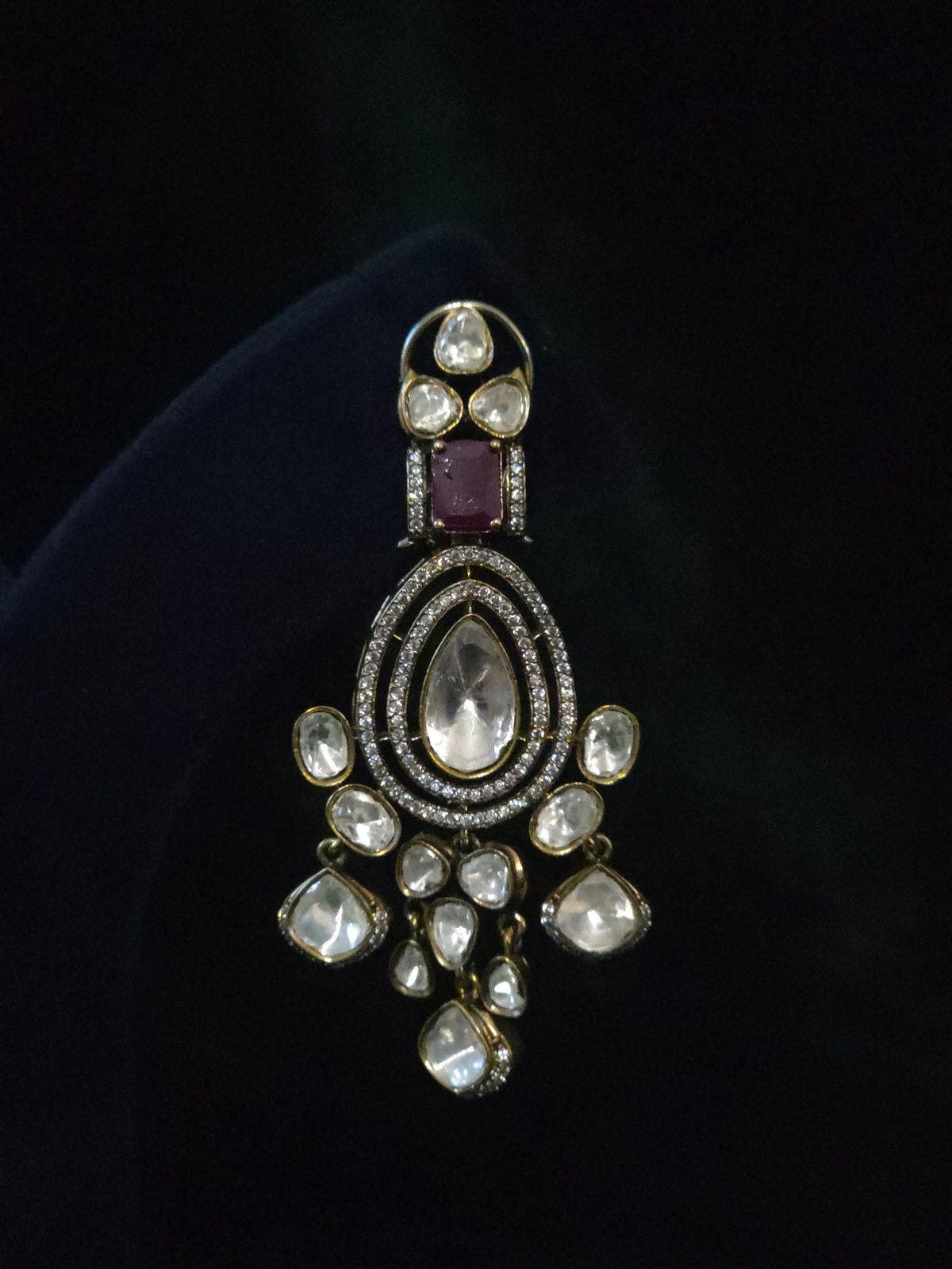 Close-up of a pear and rose-cut CZ chandelier earring with ruby accent