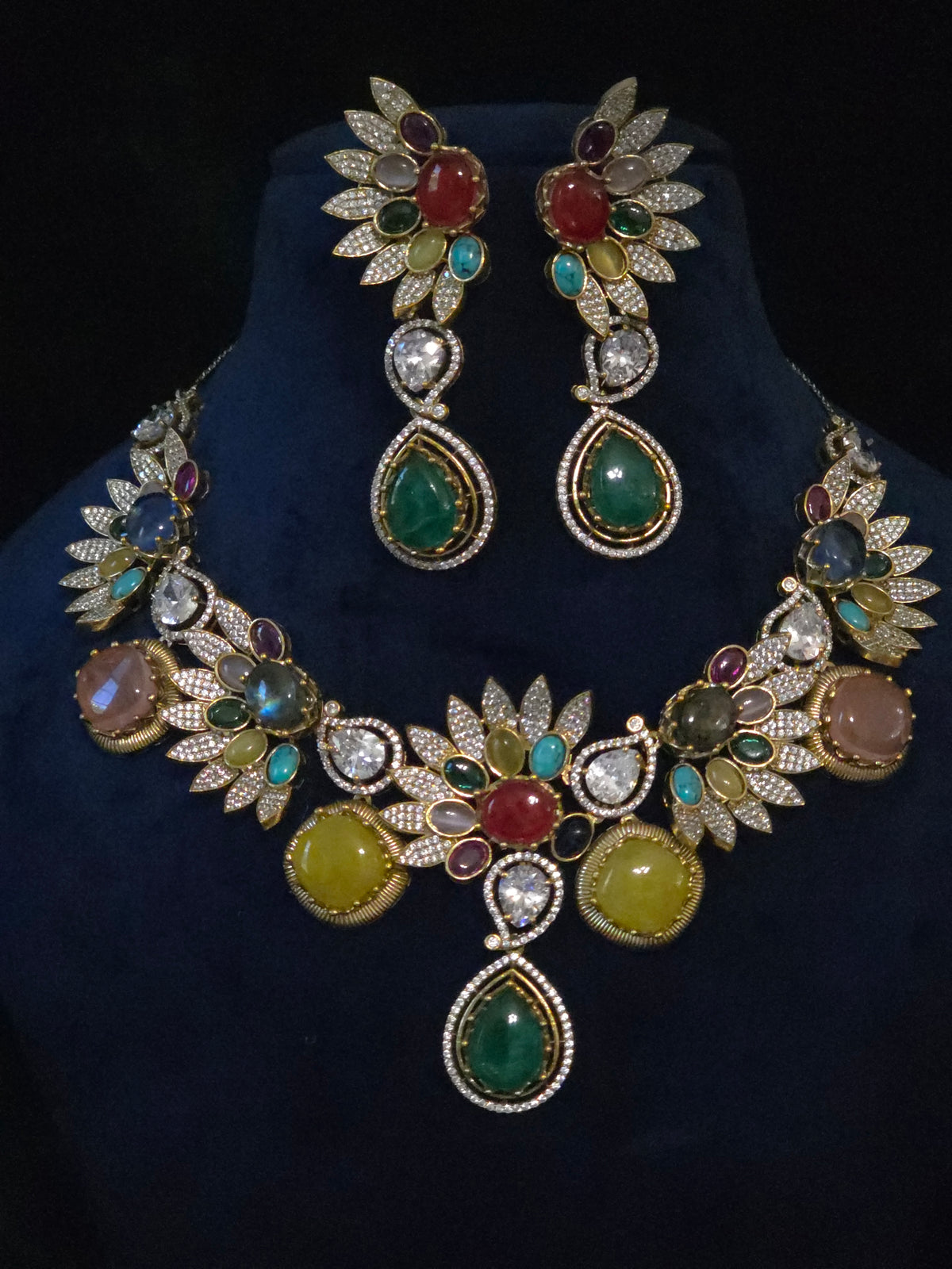 Close-up of multicolor gemstone leaf necklace showing pave leaf motifs and emerald pear drop pendant