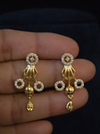 A pair of gold-toned traditional Indian jhumka earrings embellished with clear pavé stones in circular motifs and dangling bell charms,
