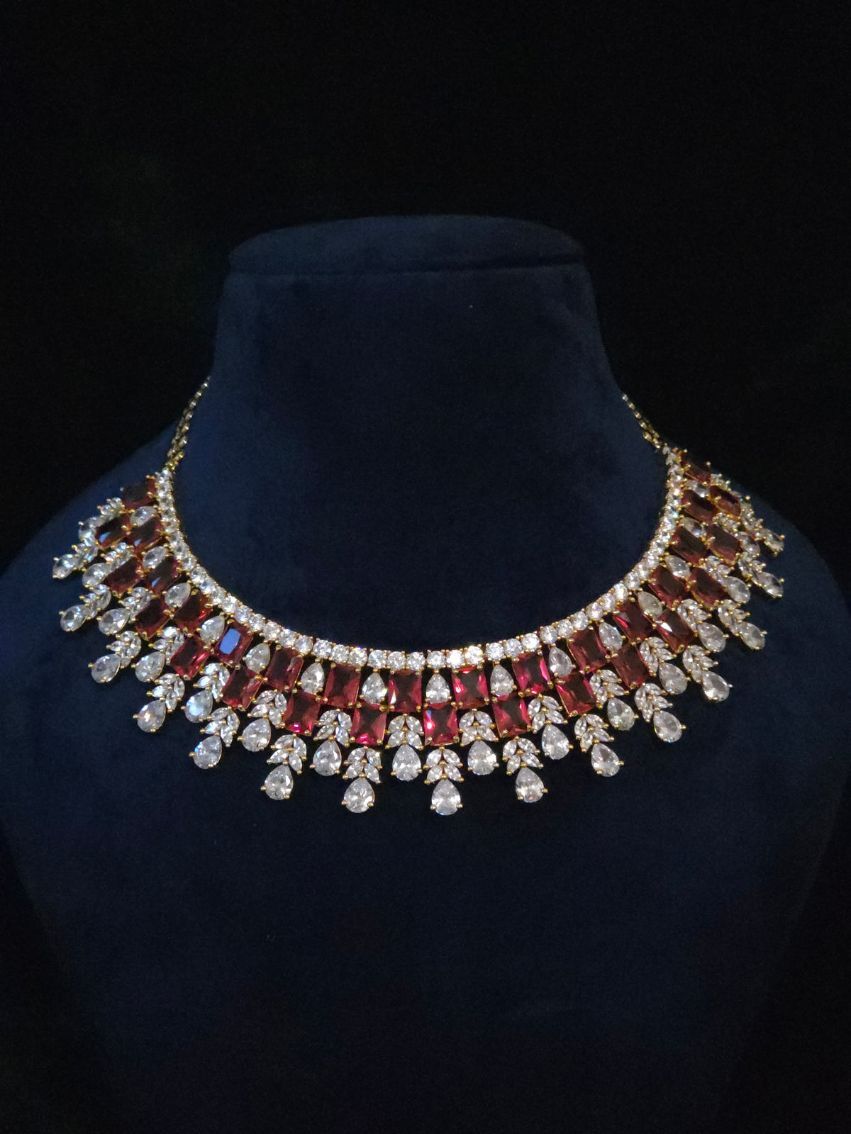 Gold-plated ruby CZ bridal choker with emerald-cut red stones and clear CZ fringe drops on a mannequin bust