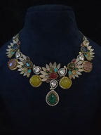 Multicolor gemstone leaf necklace and matching drop earrings displayed together on a jewelry stand
