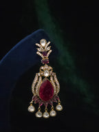 Close-up of a matching chandelier earring with wine-red stones, clear accents, and teardrop dangles
