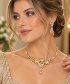 A woman wearing an ornate gold and silver jewelry set, featuring a matching necklace and earring with intricate floral and fan-like details, set against a softly blurred warm background.