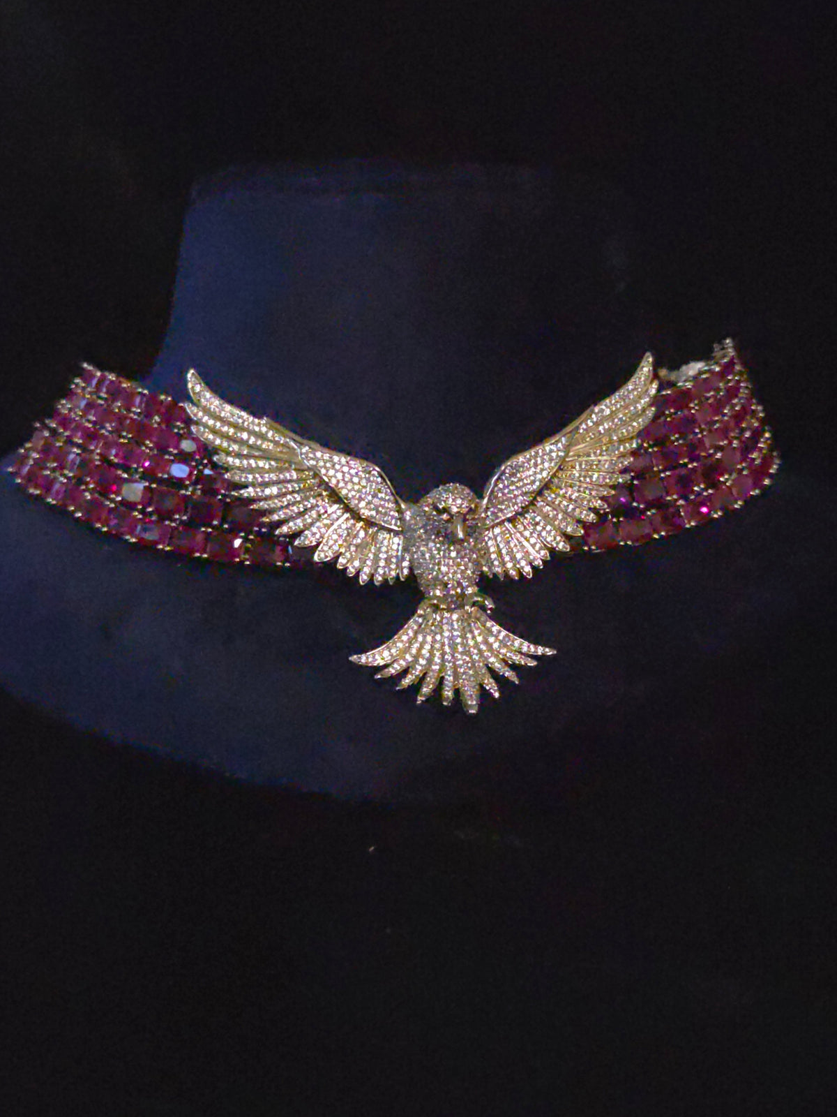 Close-up of ruby CZ collar necklace showing the pave bird pendant with spread wings